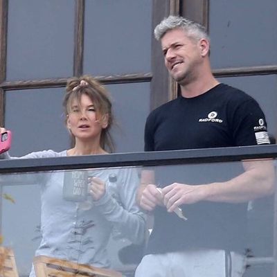 Both are standing at the balcony looking at something.